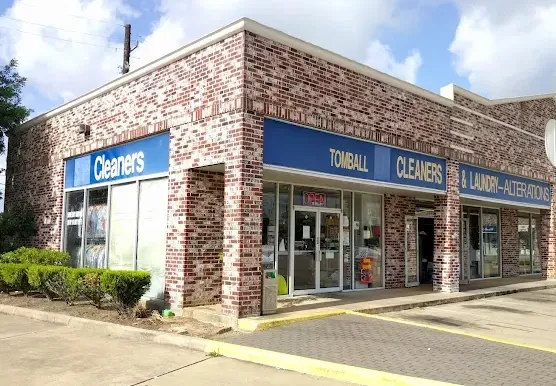Tomball Cleaners storefront with blue Tomball Cleaners and Laundry Alterations signs on a brick building